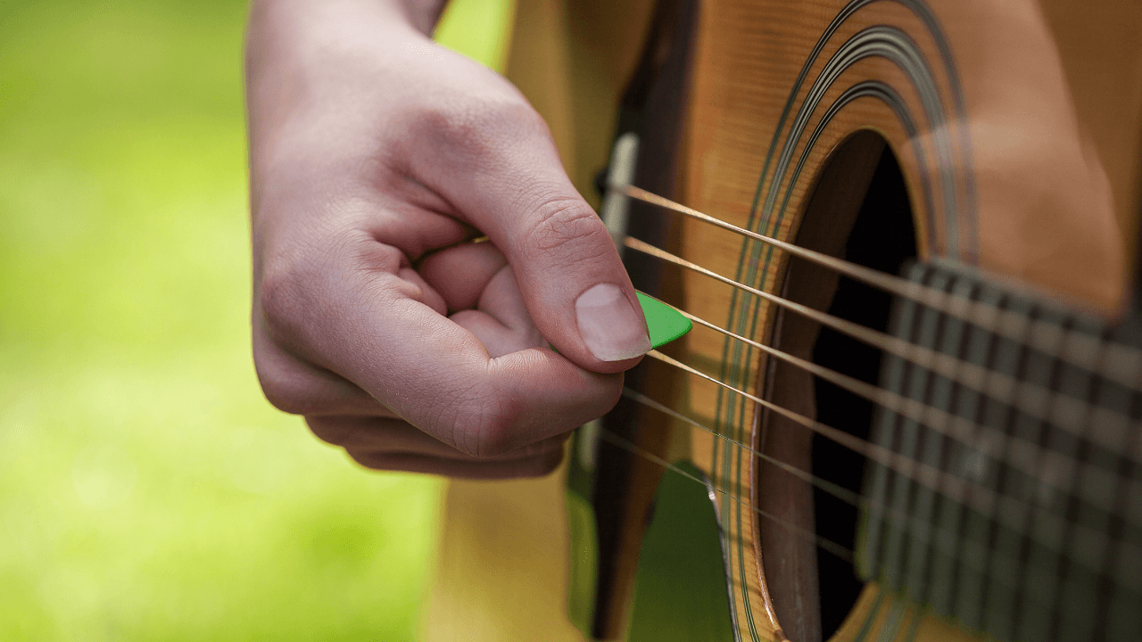 A person using a guitar pick to show how to hold a guitar pick correctly